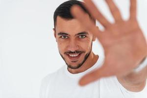 Stop gesture. Young handsome man standing indoors against white background photo