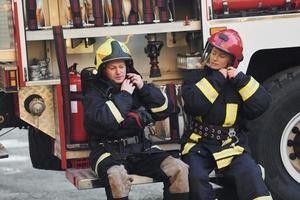 Male and female firefighters in protective uniform is outdoors together photo