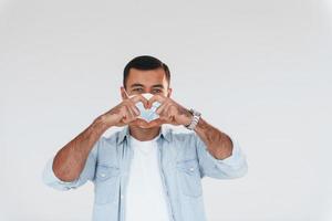 In protective mask. Young handsome man standing indoors against white background photo