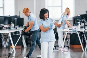 Group of workers clean modern office together at daytime photo