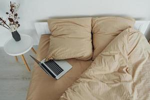 la computadora portátil está en la cama. interior y diseño de hermoso dormitorio moderno durante el día foto