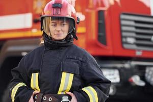 Female firefighter in protective uniform standing near truck photo