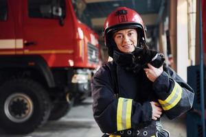 Cute black cat. Female firefighter in protective uniform standing near truck photo