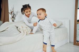 Two kids have fun while liyng down on bed. Interior and design of beautiful modern bedroom at daytime photo