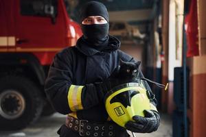 Portrait of firefighter in protective uniform that holds cute little black cat photo