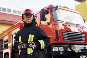 Female firefighter in protective uniform standing near truck photo