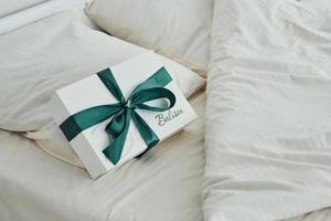 la caja de regalo está en la cama blanca. interior y diseño de hermoso dormitorio moderno durante el día foto