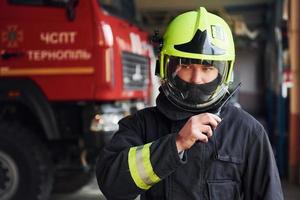 Male firefighter in protective uniform standing near truck photo