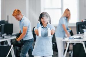 Group of workers clean modern office together at daytime photo