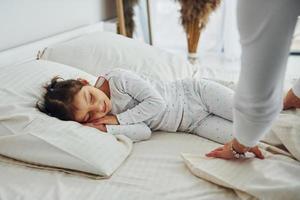 la niña duerme y mamá miró y ella. interior y diseño de hermoso dormitorio moderno durante el día foto