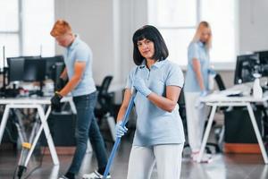 Group of workers clean modern office together at daytime photo