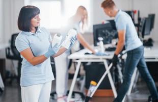 Group of workers clean modern office together at daytime photo