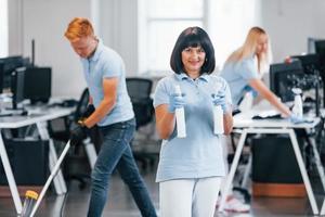 Group of workers clean modern office together at daytime photo