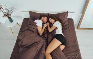 linda pareja acostada en la cama juntos. interior y diseño de hermoso dormitorio moderno durante el día foto