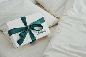 la caja de regalo está en la cama blanca. interior y diseño de hermoso dormitorio moderno durante el día foto