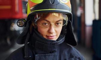 Close up view. Female firefighter in protective uniform standing near truck photo