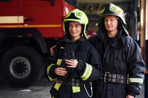 Bomberos masculinos y femeninos en uniforme protector de pie juntos foto
