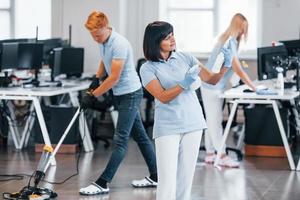 Group of workers clean modern office together at daytime photo