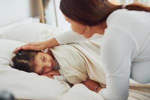 la niña duerme y mamá miró y ella. interior y diseño de hermoso dormitorio moderno durante el día foto