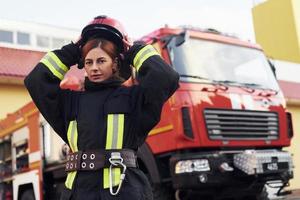 Female firefighter in protective uniform standing near truck photo