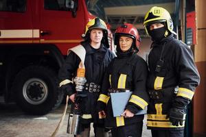 posando para una cámara. grupo de bomberos con uniforme protector que está en la estación foto