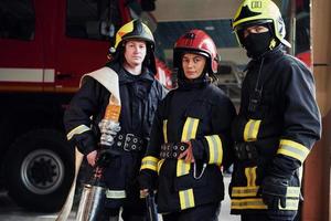 posando para una cámara. grupo de bomberos con uniforme protector que está en la estación foto