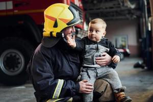 un niño lindo está con un bombero con uniforme protector foto