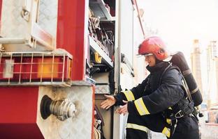 Takes equipment. Female firefighter in protective uniform standing near truck photo