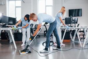 Concentrated at job. Group of workers clean modern office together at daytime photo