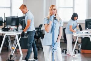 Cleans floor. Group of workers clean modern office together at daytime photo