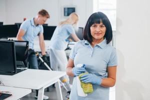 Group of workers clean modern office together at daytime photo