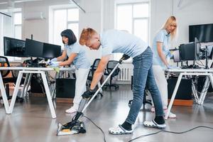 Concentrated at job. Group of workers clean modern office together at daytime photo