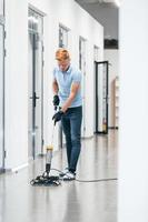 Young man works in the modern office. Uses vacuum cleaner photo