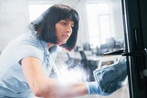 Woman cleaning dirty window by using towel. View through the glass photo