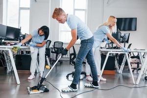 Concentrated at job. Group of workers clean modern office together at daytime photo