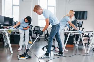 Concentrated at job. Group of workers clean modern office together at daytime photo