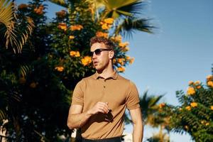 In sunglasses. Young man is outdoors at sunny daytime. Concept of vacation photo