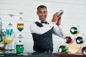 At the bar. Black waiter in formal clothes is at his work outdoors at sunny daytime photo