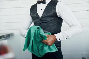 Black waiter in formal clothes is at his work outdoors at sunny daytime photo