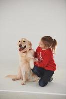 Little girl is with cute Golden retriever in the studio against white background photo