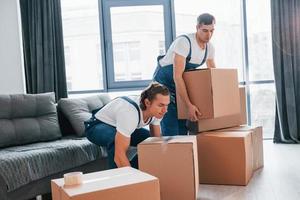 Día ocupado. dos jóvenes motores con uniforme azul trabajando en el interior de la habitación foto