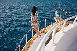 Mature woman standing on the yacht and enjoying her vacation on the sea photo