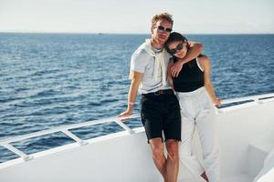 Cheerful young couple standing on the yacht on the sea. Conception of vacation photo