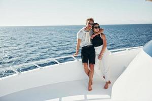 Cheerful young couple standing on the yacht on the sea. Conception of vacation photo