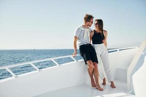 Cheerful young couple standing on the yacht on the sea. Conception of vacation photo
