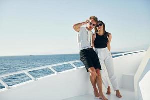 Cheerful young couple standing on the yacht on the sea. Conception of vacation photo