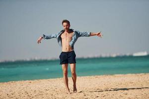 divirtiéndose. joven europeo tiene vacaciones y disfruta del tiempo libre en la playa del mar foto