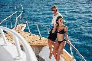 Cheerful young couple standing on the yacht on the sea. Conception of vacation photo