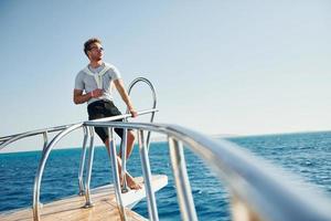 Posing for a camera. Young male tourist is on the yacht on the sea. Conception of vacation photo