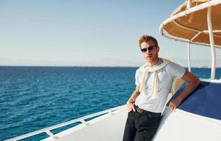 Young male tourist is on the yacht on the sea. Conception of vacation photo